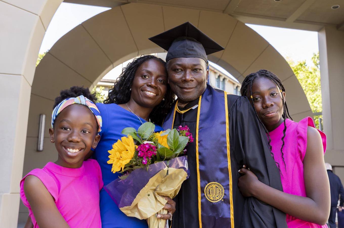 EMBA student poses with wife and children at graduation