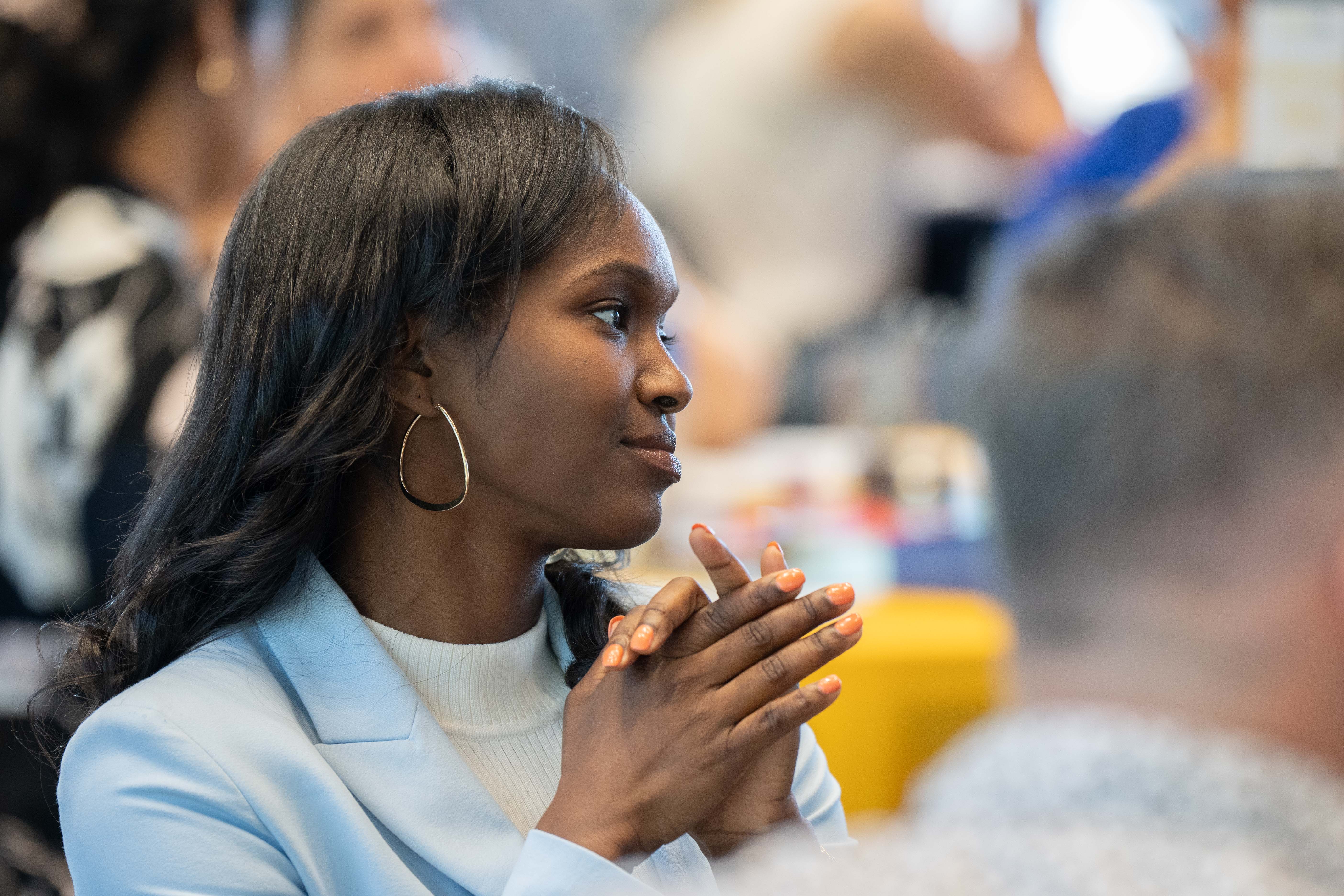 Female student smiles and listens to a speaker at EMBA orientation